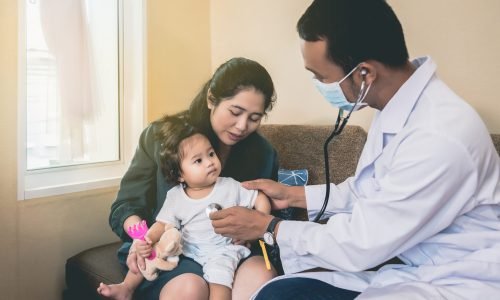 An Asian doctor is checking the symptoms of a sick girl and having her mother with her.